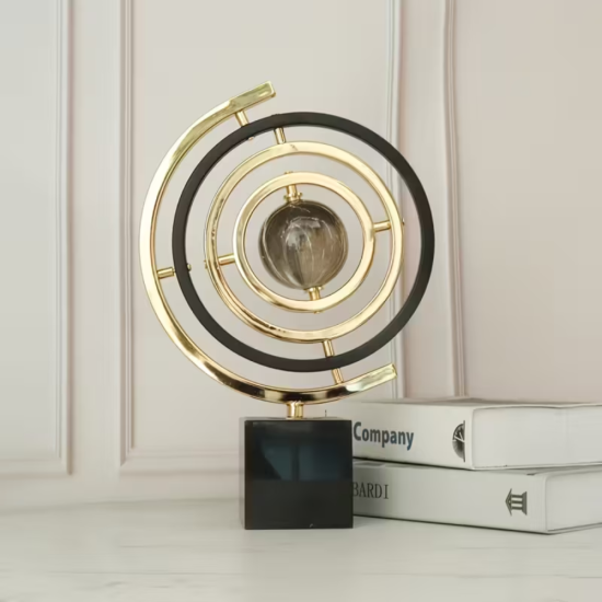 Декоративна армирална сфера от метал в златист и черен цвят, поставена върху масивна квадратна основа от черен мрамор