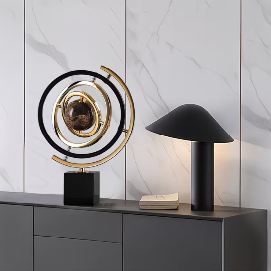 Декоративна армирална сфера от метал в златист и черен цвят, поставена върху масивна квадратна основа от черен мрамор