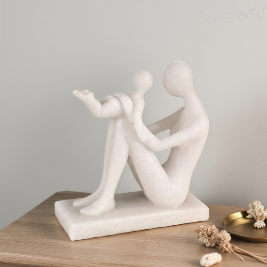 Бяла статуетка на майка, седнала на земята и вдигнала бебето си във въздуха