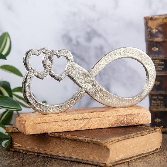 Метална статуетка във формата на знак за безкрайност с вплетени две сърца, поставена върху основа от естествено дърво