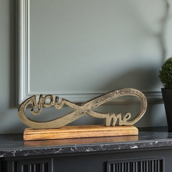 Метална статуетка във формата на знак за безкрайност с вплетени думи "you" и "me", поставена на дървена основа