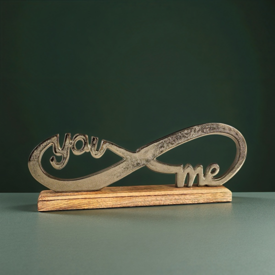Метална статуетка във формата на знак за безкрайност с вплетени думи "you" и "me", поставена на дървена основа