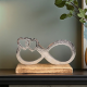 Метална статуетка във формата на знак за безкрайност с две вплетени сърца в единия край, поставена на дървена основа