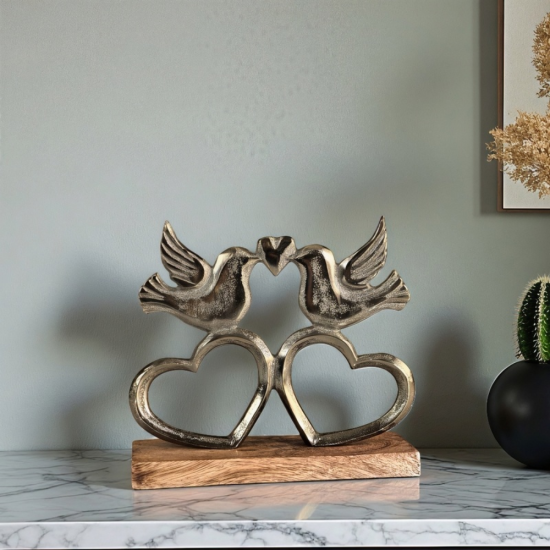 Метална статуетка на две птици, докосващи човки, образувайки сърце, поставени върху дървена основа