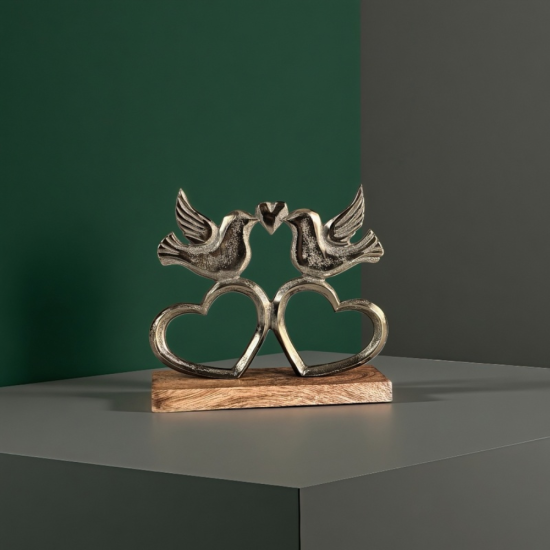 Метална статуетка на две птици, докосващи човки, образувайки сърце, поставени върху дървена основа