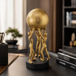 Релефна златна статуетка на три човешки фигури, поддържащи голяма сфера, позиционирана върху тъмно кожено бюро