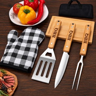 Инструменти за скара с надпис BBQ, подредени върху дървена дъска до карирана ръкавица, прясно изпечено месо и свежи чушки